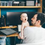 Father working from home with chilld in his arms